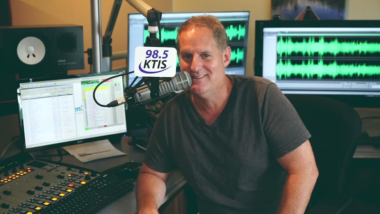 A man is sitting in the radio room at the microphone