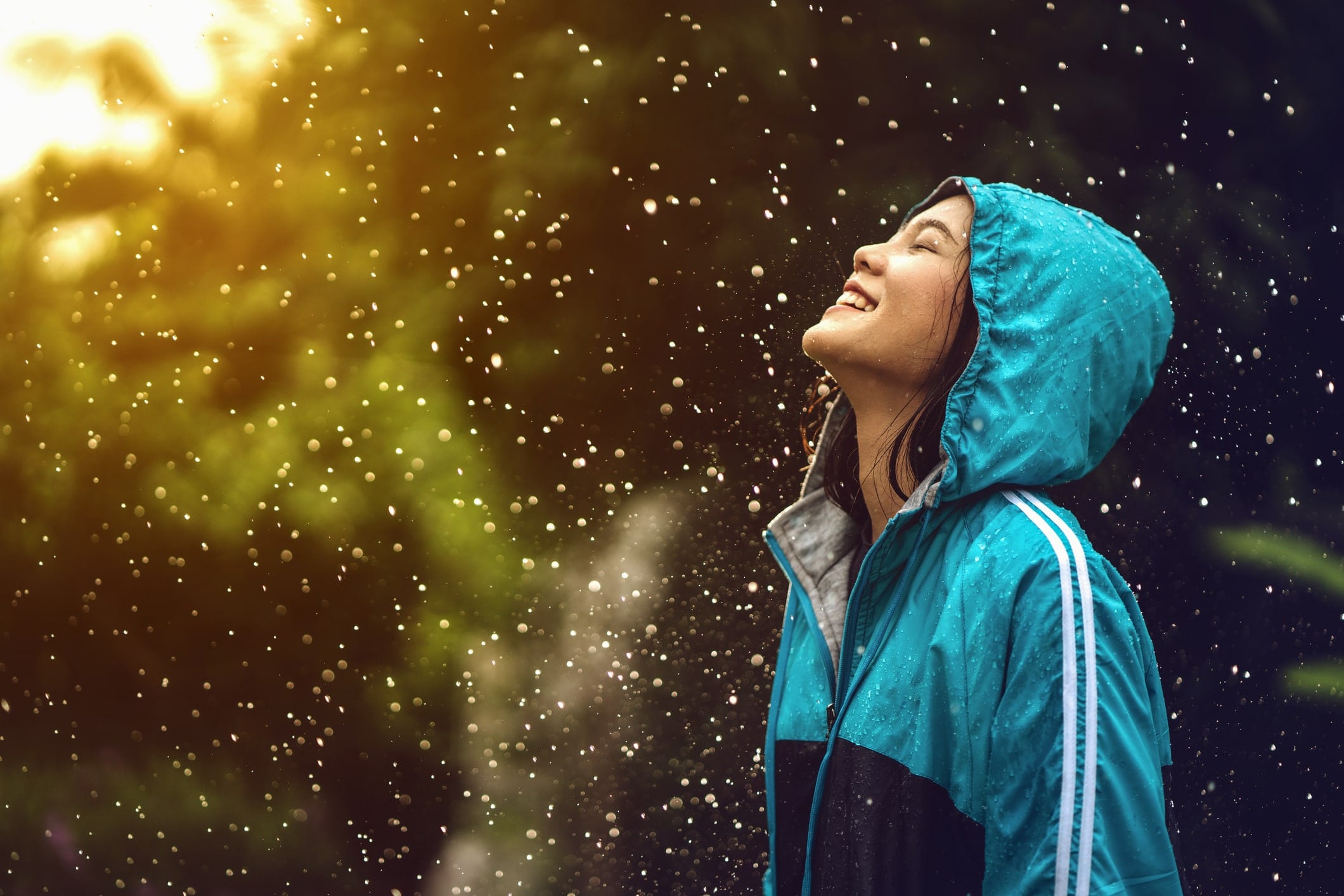 A smiling girl with a hood on her head, is raining