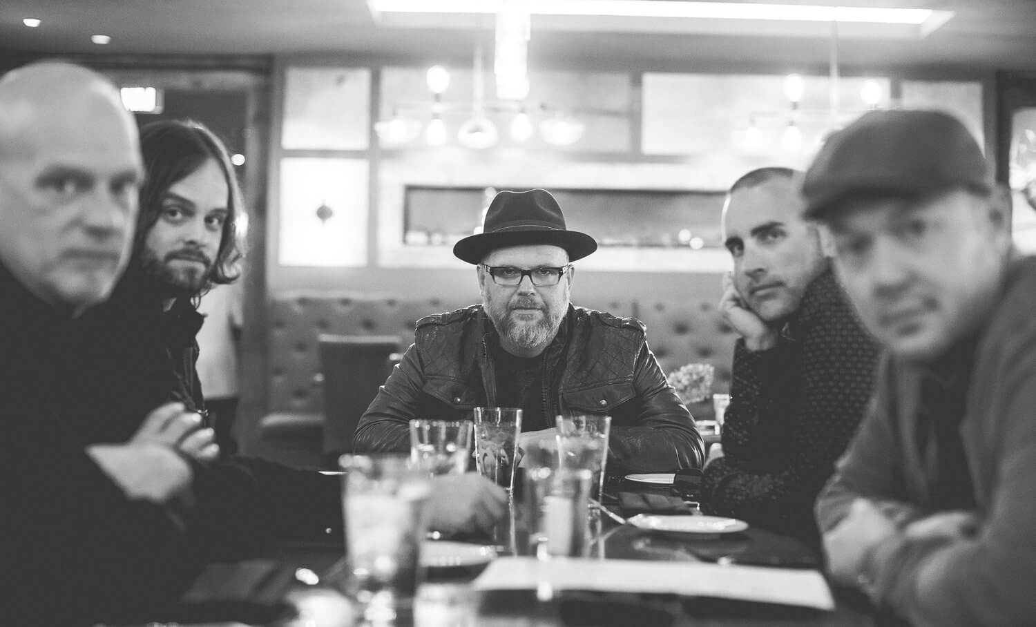 Five men sitting around a table looking into the camera