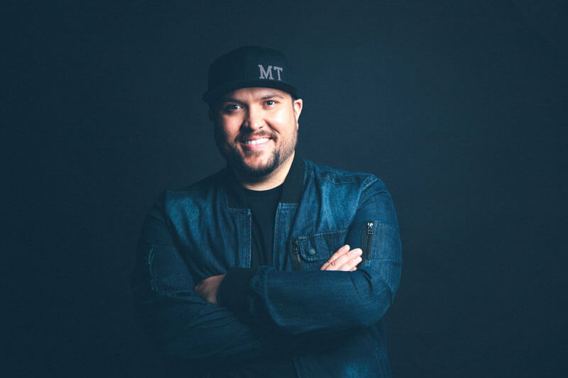 A man in a baseball cap poses smiling for a photo