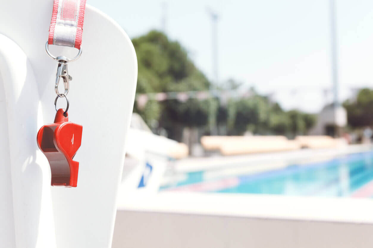 Close-up of a whistle against the backdrop of an outdoor swimming pool