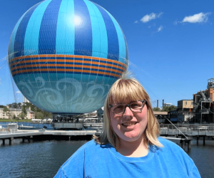 A woman in glasses and a blue blouse in the background of a flying balloon
