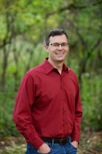 Smiling standing man in red shirt and glasses