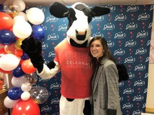 A woman posing for a photo with a cow mascot