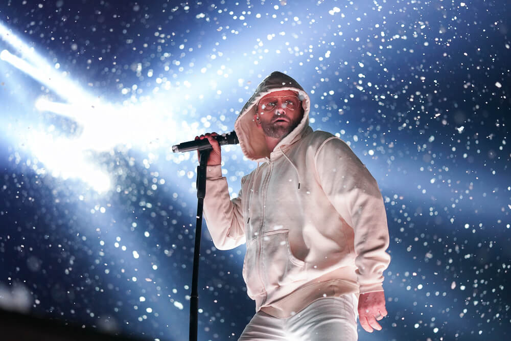 TobyMac singing into a microphone in a white outfit