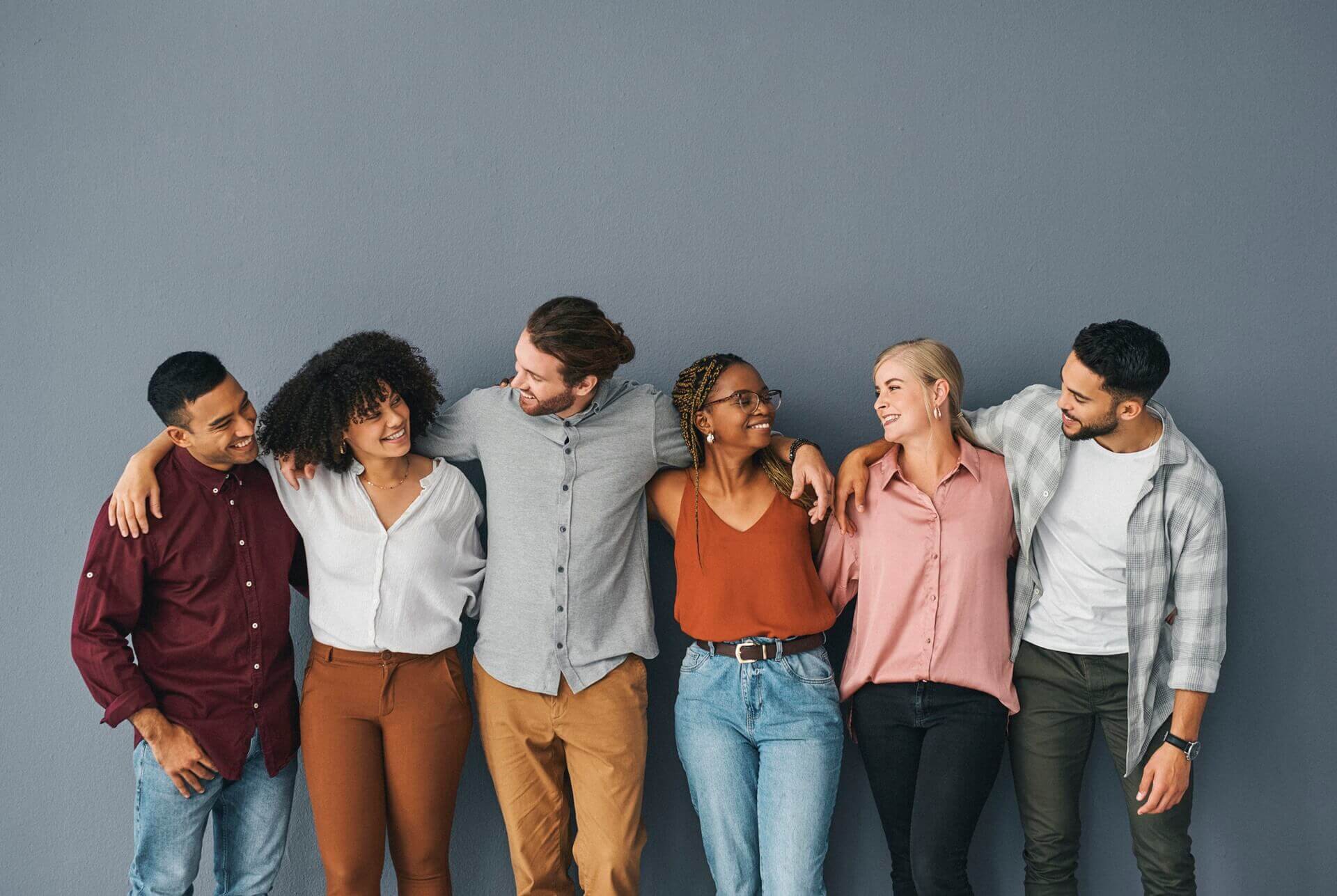 Young and diverse group of businesspeople standing together against a grey background