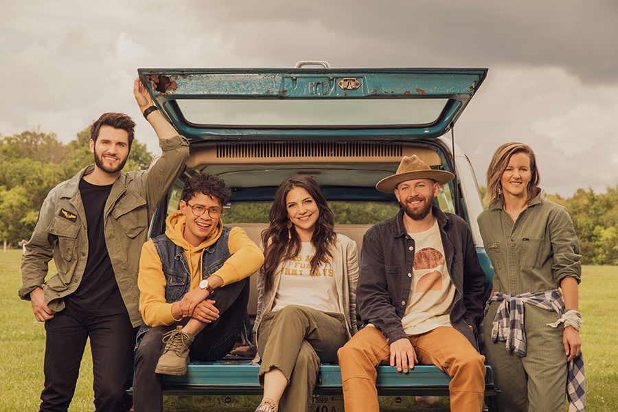 Young people sitting and leaning on a car