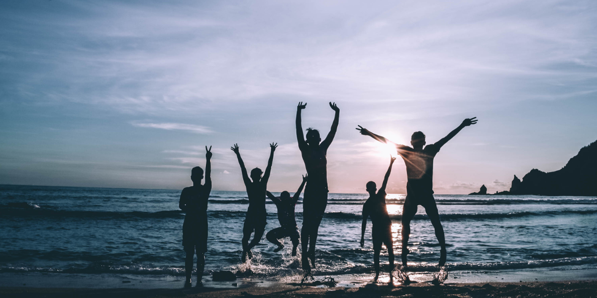 A family waving on the beach during twilight