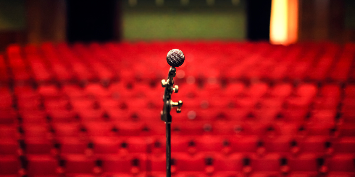 A microphone on a stage looking out over lots of empty red seats