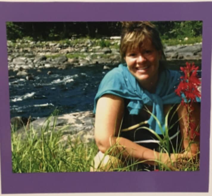 Keith's wife Sue next to red wildflowers.