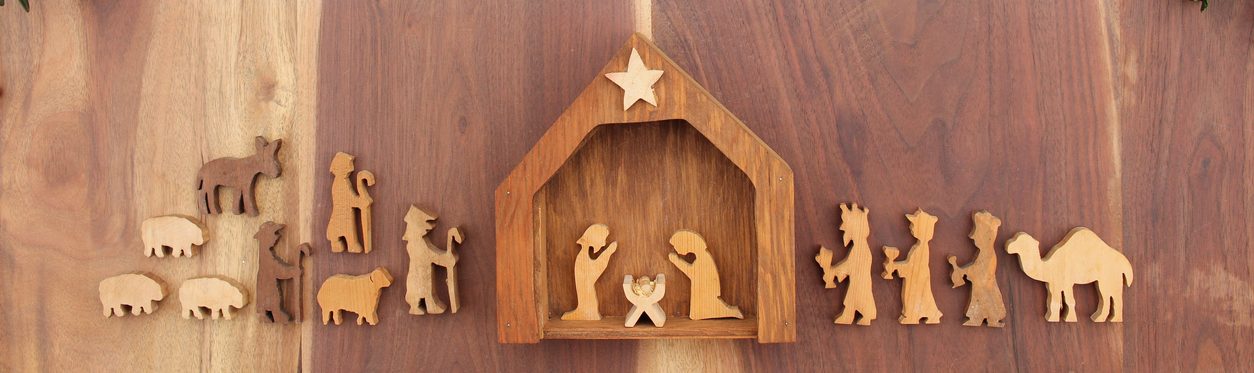 Christmas nativity on a wood background with red berries and greenery