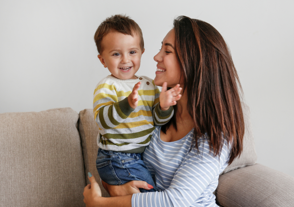 Olivia from the Dwelling Place sitting on the couch smiling with her little boy who is smiling happily