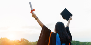 A graduate holding up her diploma and cap as she praises God