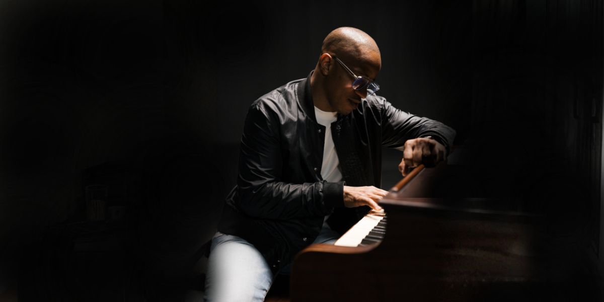 Jon Reddick at the piano in a contrasting dark atmosphere