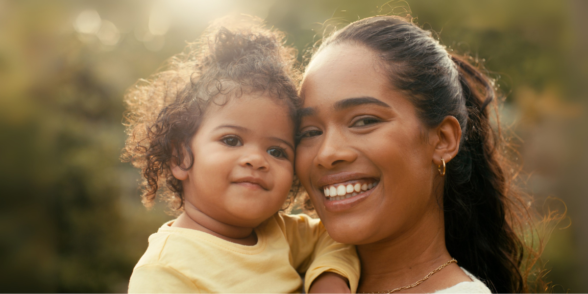 A mom and her baby smiling on a warm, sunny day.